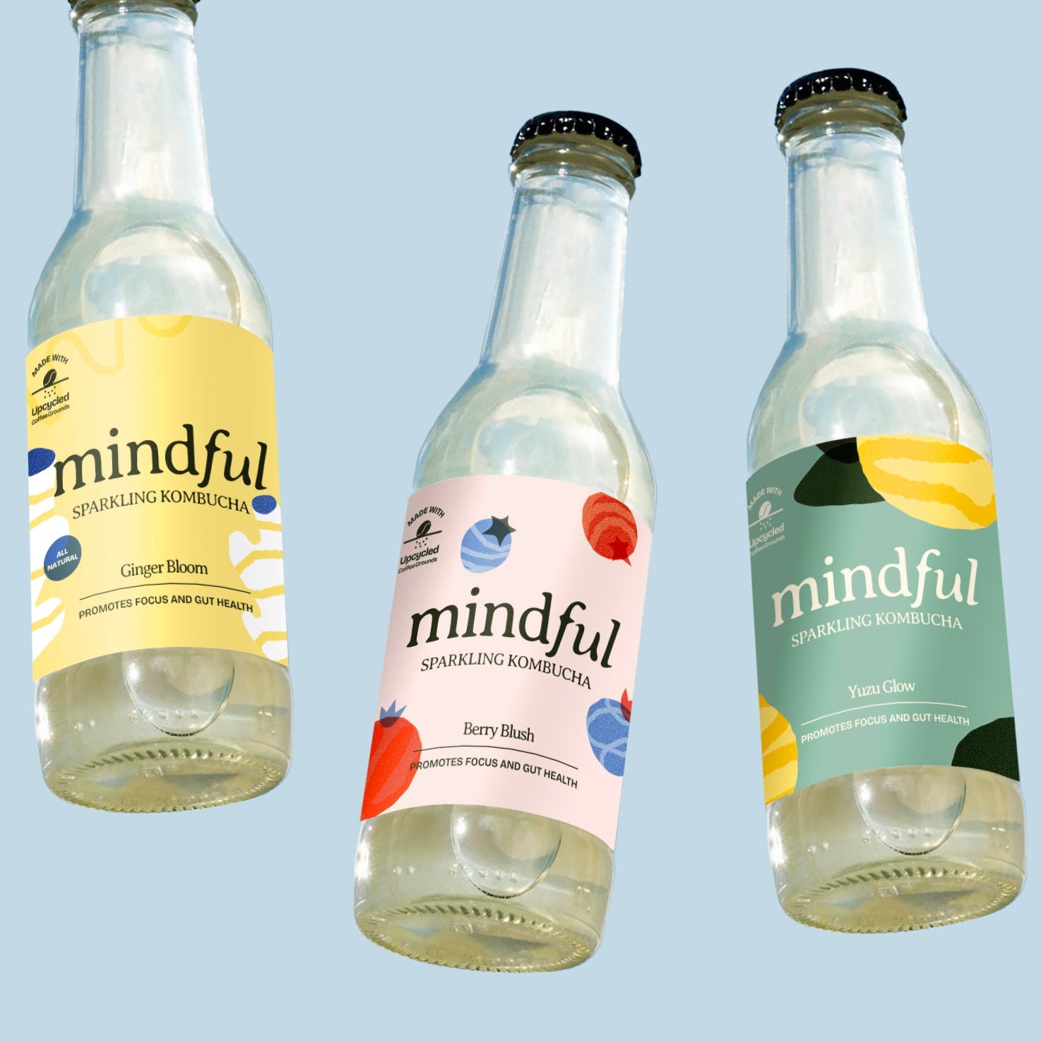 Three bottles of 'mindful' sparkling kombucha on a light blue background